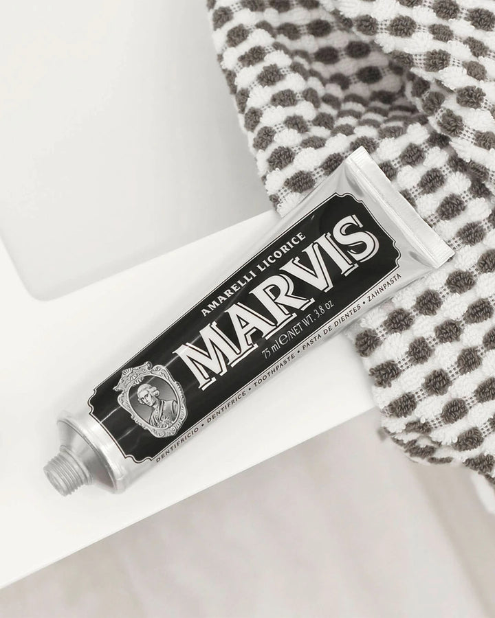 Marvis toothpaste tube on a white surface with a checkered towel