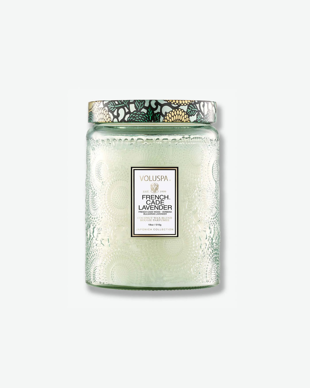 Front view of a Voluspa French Cade Lavender large jar candle against a plain gray background. The translucent, pale sage green glass jar features an intricate embossed floral texture, a central white label, and a patterned tin lid decorated with a green, black, and gold botanical design.