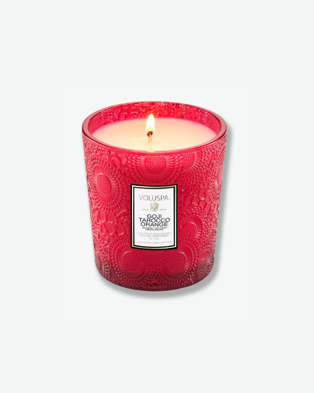 Product shot showcasing a Voluspa Goji Tarocco Orange classic textured glass candle next to its square outer box. The red glass candle vessel features a tapered shape and a central white product label, sitting beside a box patterned with the signature red, gold, and black Japonica floral design.
