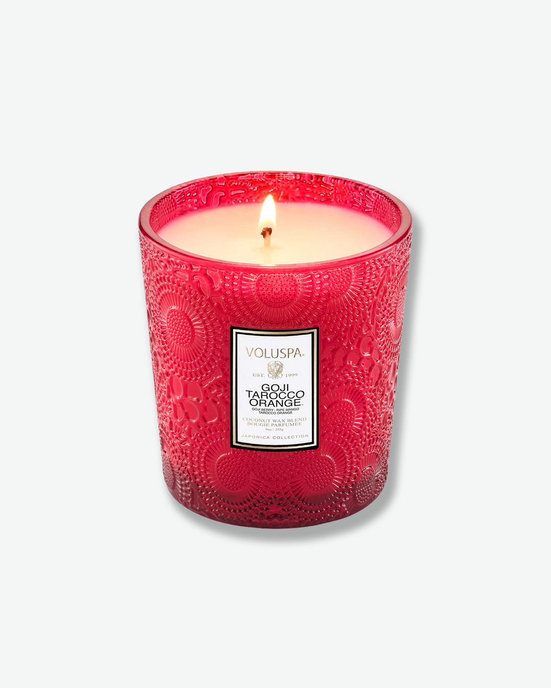 Product shot showcasing a Voluspa Goji Tarocco Orange classic textured glass candle next to its square outer box. The red glass candle vessel features a tapered shape and a central white product label, sitting beside a box patterned with the signature red, gold, and black Japonica floral design.
