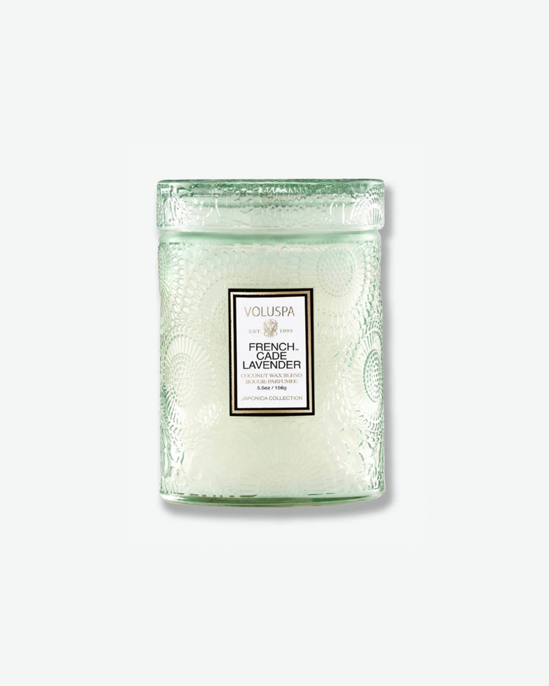 Front view of a Voluspa French Cade Lavender small jar candle against a plain gray background. The candle is housed in a translucent, pale sage green glass container embossed with a detailed botanical pattern and features a central white label, topped with a matching textured glass lid.