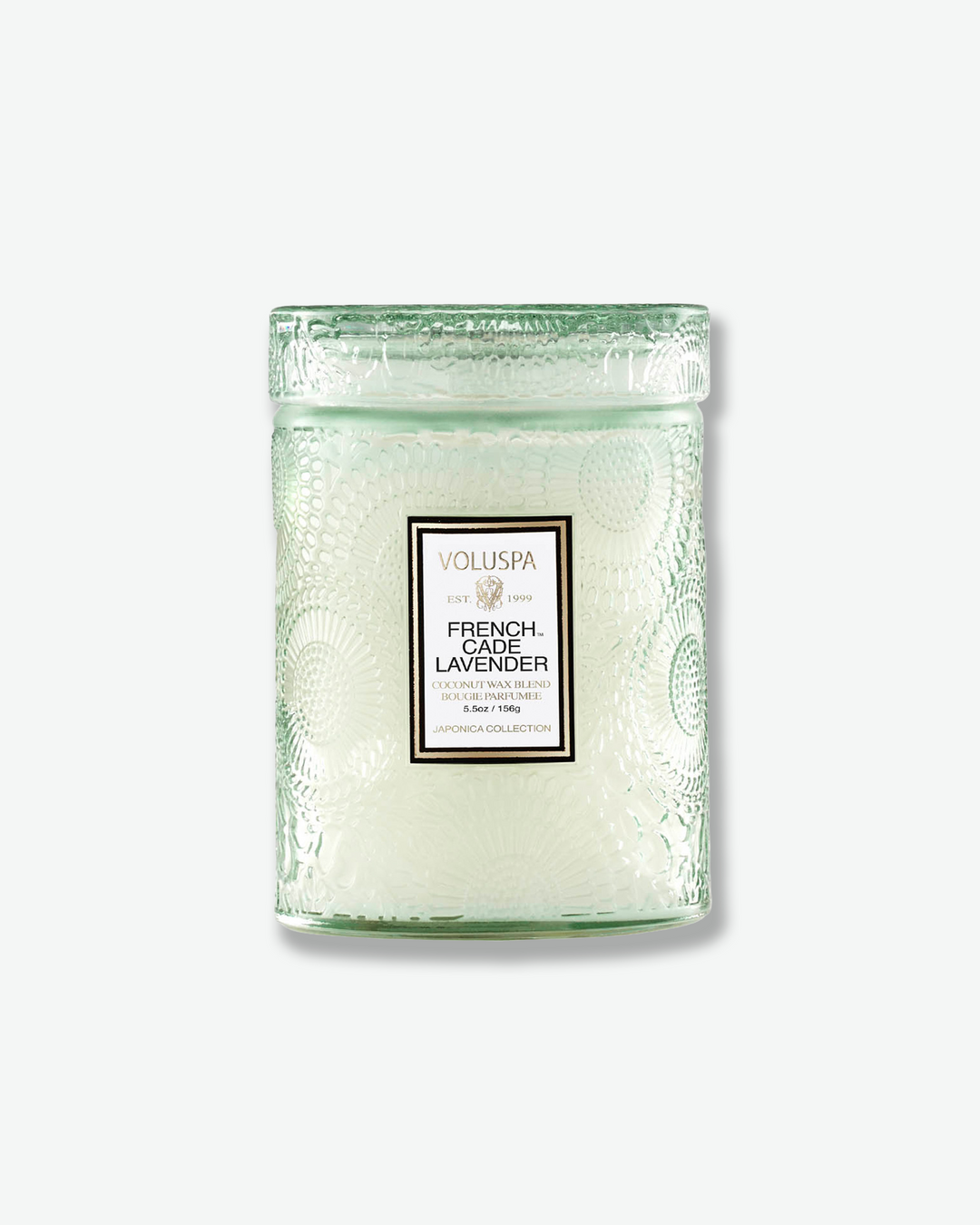 Front view of a Voluspa French Cade Lavender small jar candle against a plain gray background. The candle is housed in a translucent, pale sage green glass container embossed with a detailed botanical pattern and features a central white label, topped with a matching textured glass lid.
