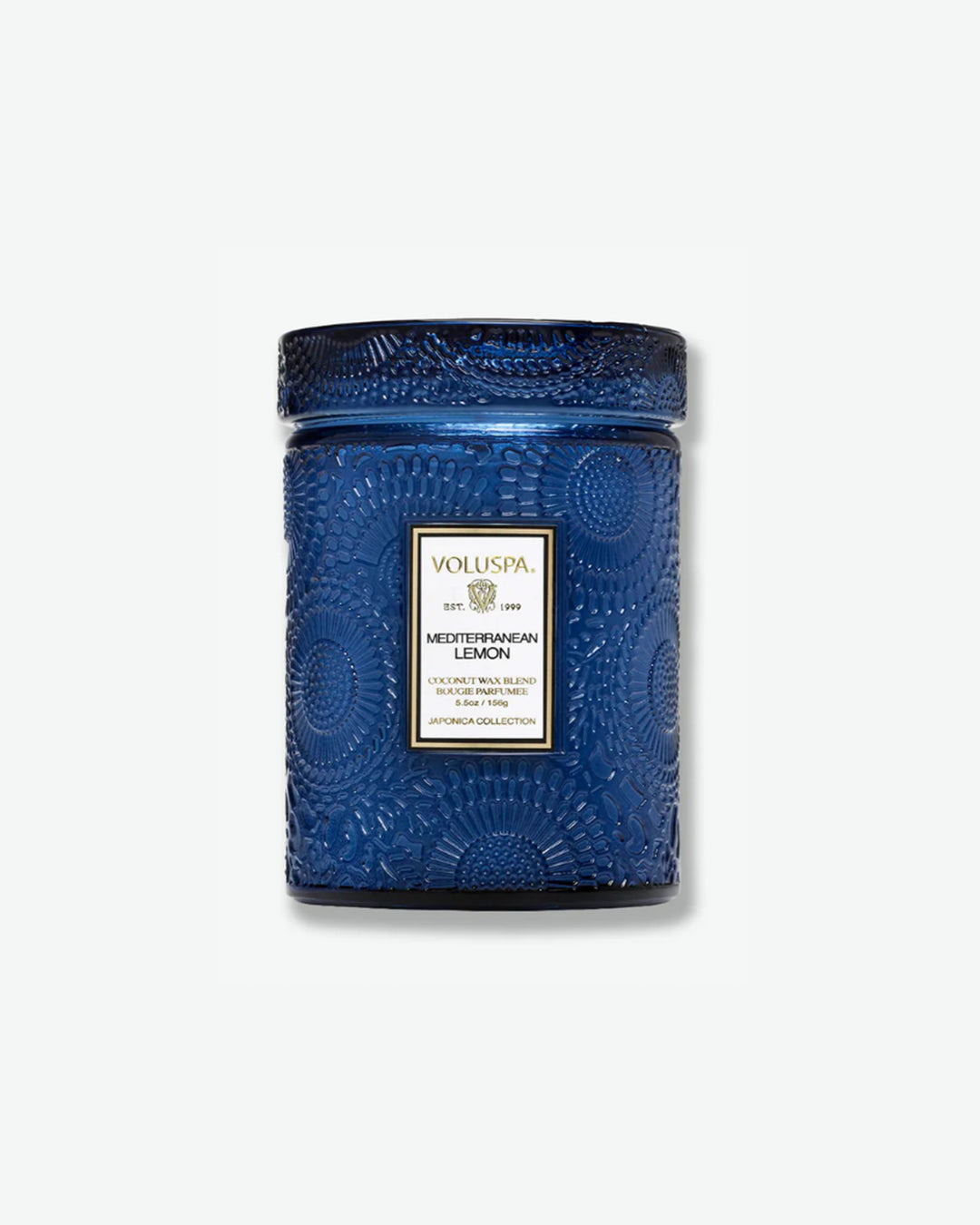 Front view of a Voluspa Mediterranean Lemon small jar candle against a plain gray background. The deep cobalt blue glass jar is intricately embossed with swirling floral textures and capped with a matching textured glass screw-on lid.