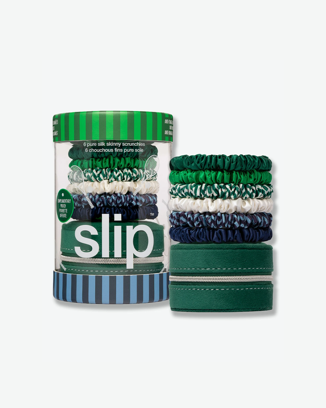 A product set featuring a Slip brand skinny silk scrunchie collection next to its packaging, isolated on a light gray background. On the left is a clear cylindrical container with a green vertically striped lid and a blue-and-navy striped base. The container displays the white word "slip" in lower-case letters and contains the stacked scrunchies resting on top of a green zippered travel pouch. On the right, the six pure silk skinny scrunchies are shown stacked directly on top of the small, round, green fabr