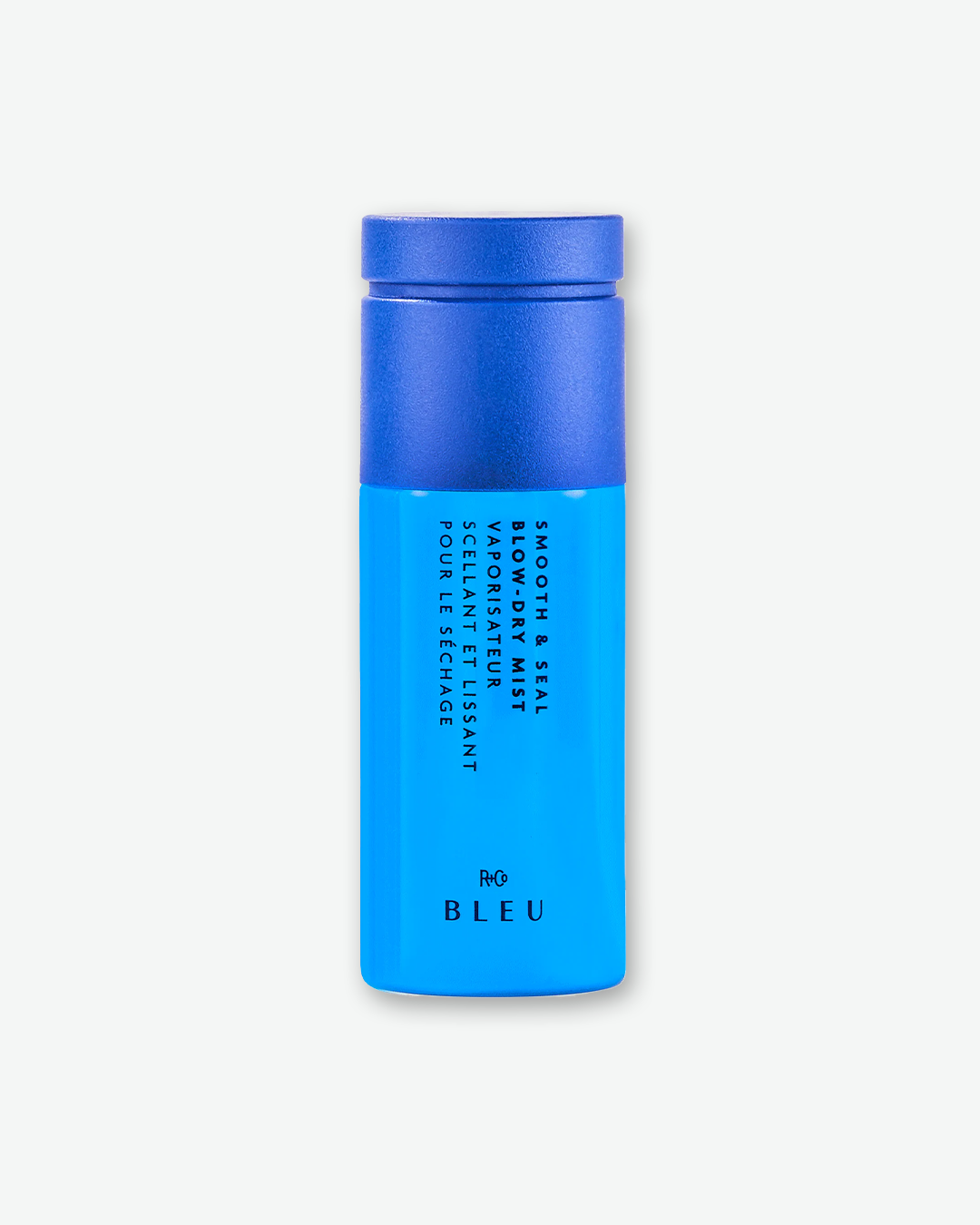 A bottle of R+Co BLEU Smooth and Seal Blow-Dry Mist on a solid light gray background. The sleek, cylindrical bottle features a deep royal blue cap and a glossy sky-blue body with the product name printed vertically.