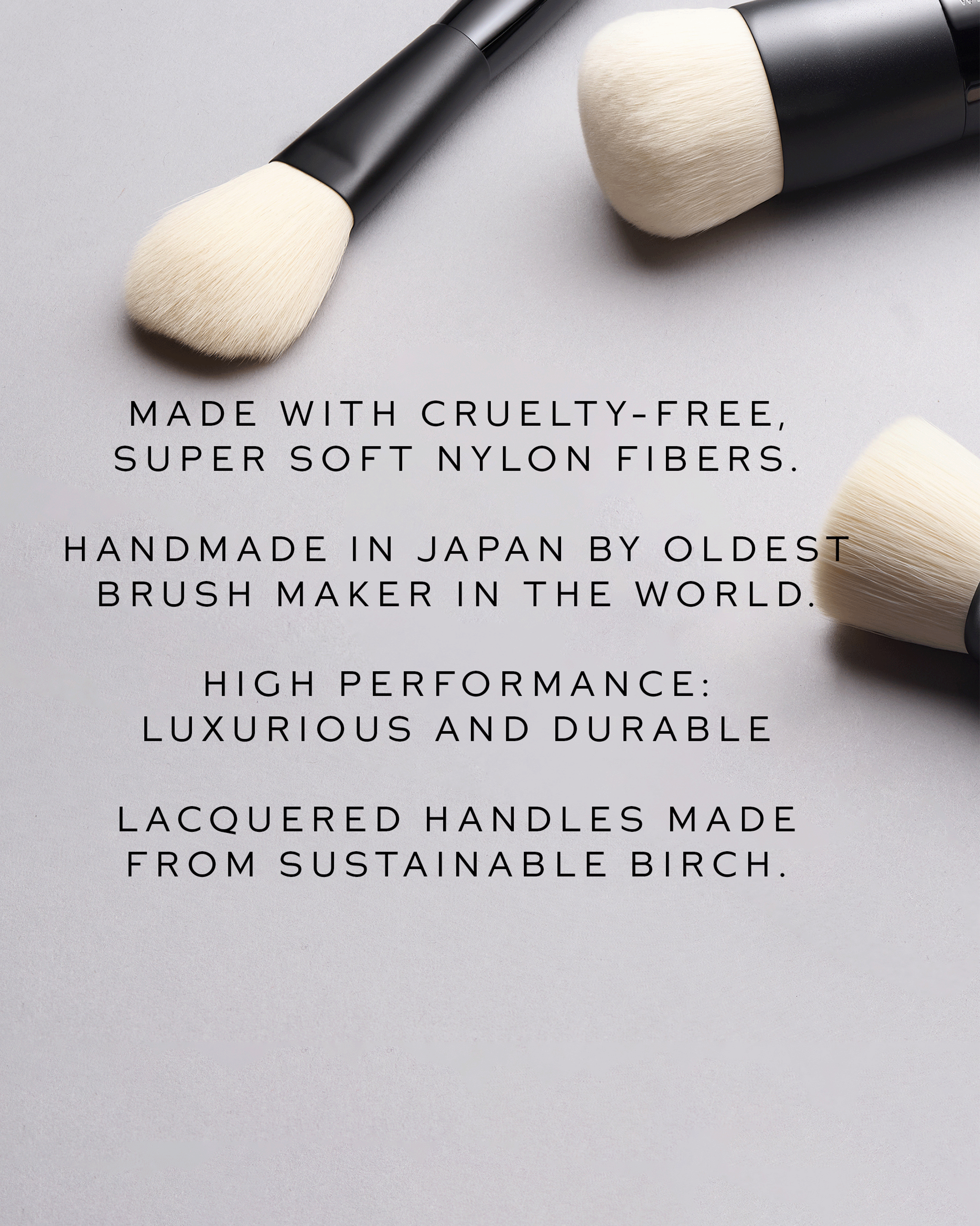 Three makeup brushes with black handles and cream bristles arranged on a light gray background, with black text describing cruelty-free nylon fibers, handmade in Japan, high performance, and sustainable birch handles.