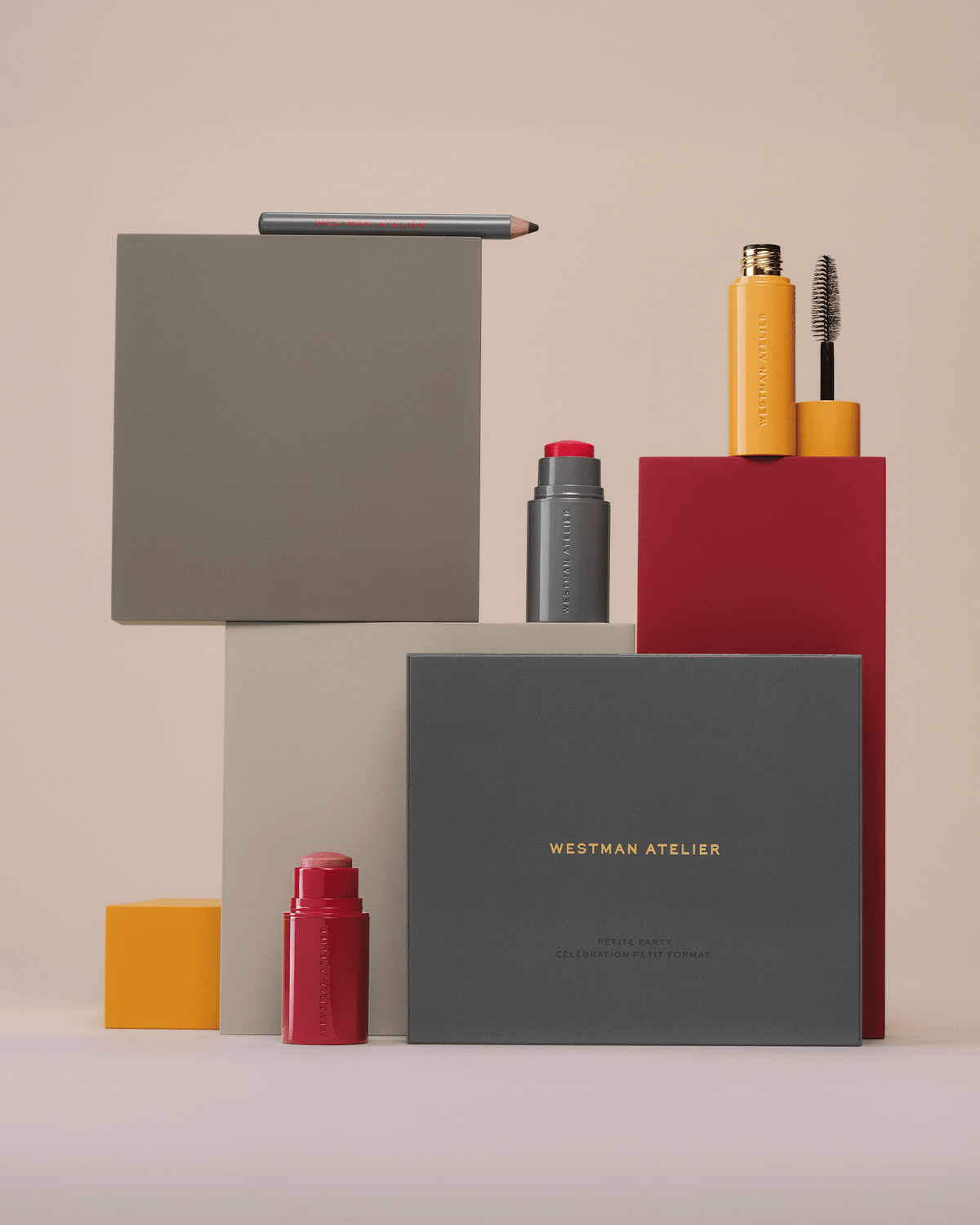 Westman Atelier Petite Party campaign still life featuring the gift box, mini blush stick, mascara, highlighter, and eye pencil displayed on sculptural blocks.