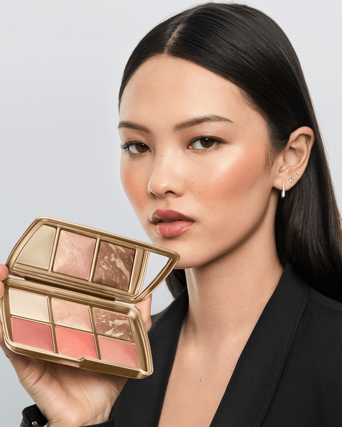 Model holding the open Hourglass Wish Palette, showcasing the six complexion shades and a softly luminous finished look.