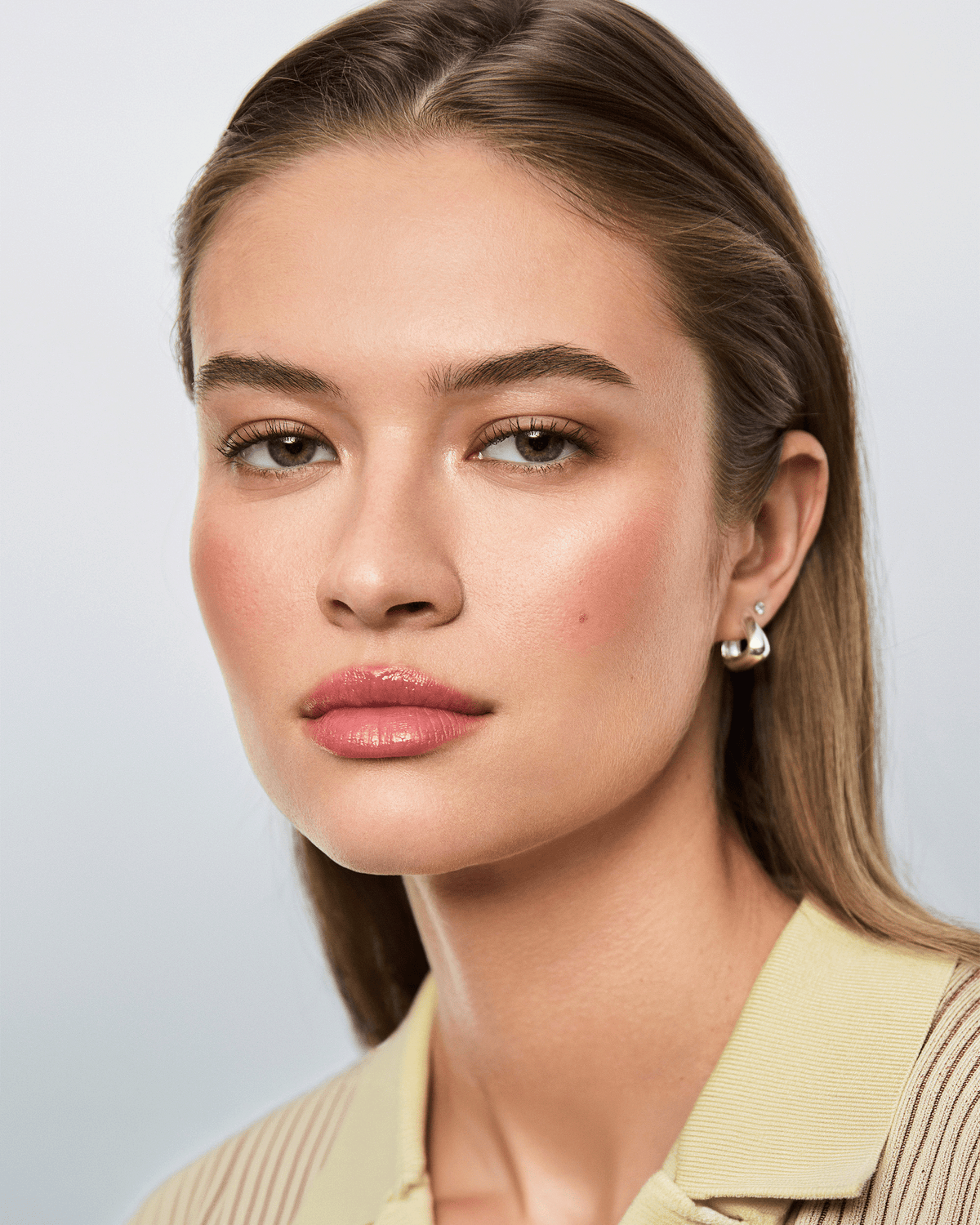Hourglass holiday beauty collection arranged beside a white vanity case, featuring the six-pan palette, dual-ended brush, mascara, and lip product in coordinated gold packaging.