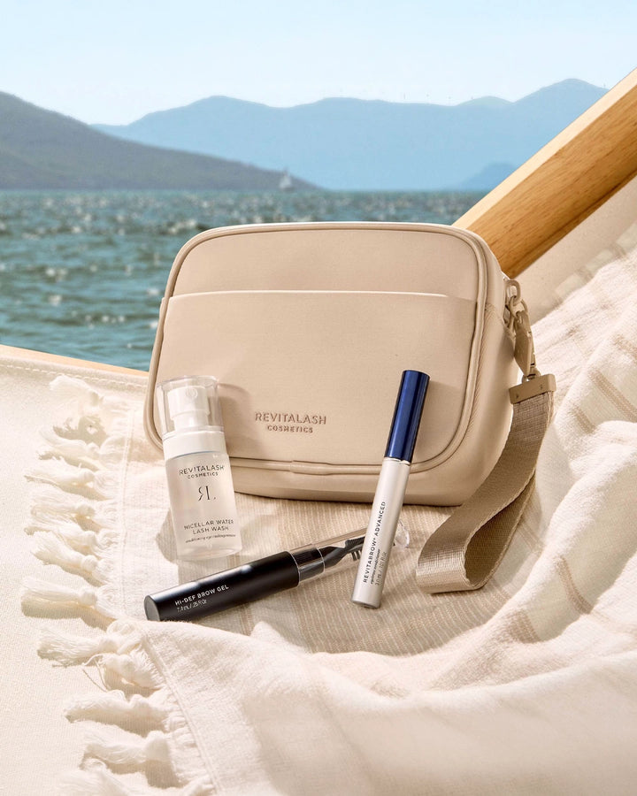 Cosmetic bag with RevitaLash products on a beach with mountains in the background