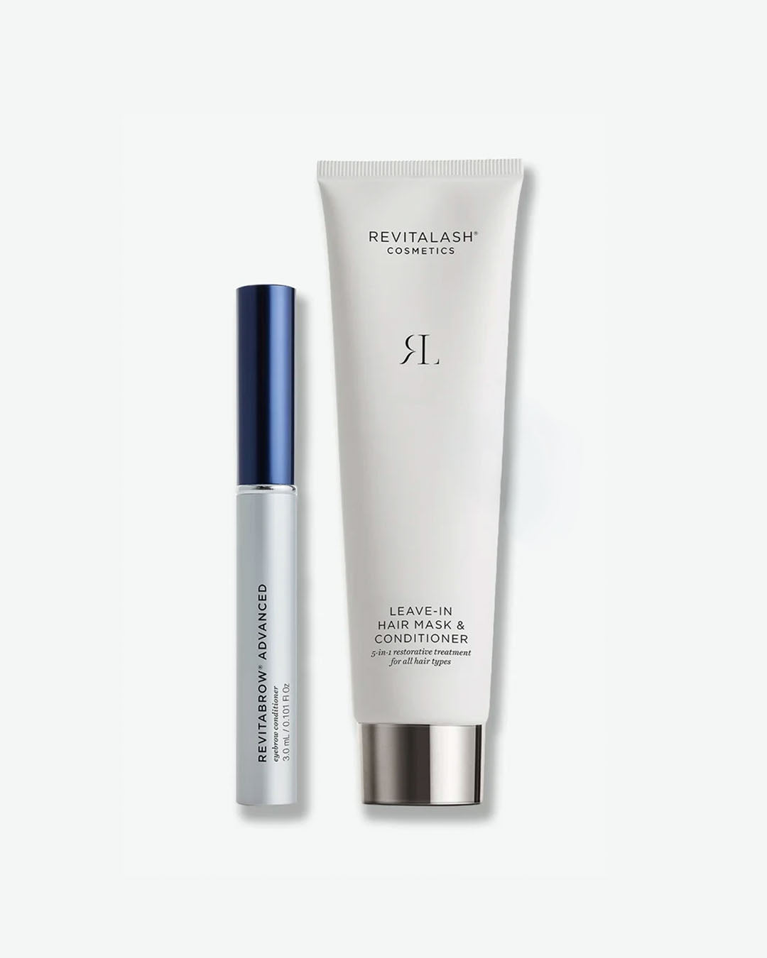 A product duo shot from RevitaLash Cosmetics against a plain white background. On the left is a slim, silver tubes of RevitaBrow Advanced Eyebrow Conditioner with a metallic blue cap. On the right stands a larger, matte white tube of Leave-In Hair Mask & Conditioner featuring minimalist black branding and a metallic silver cap.