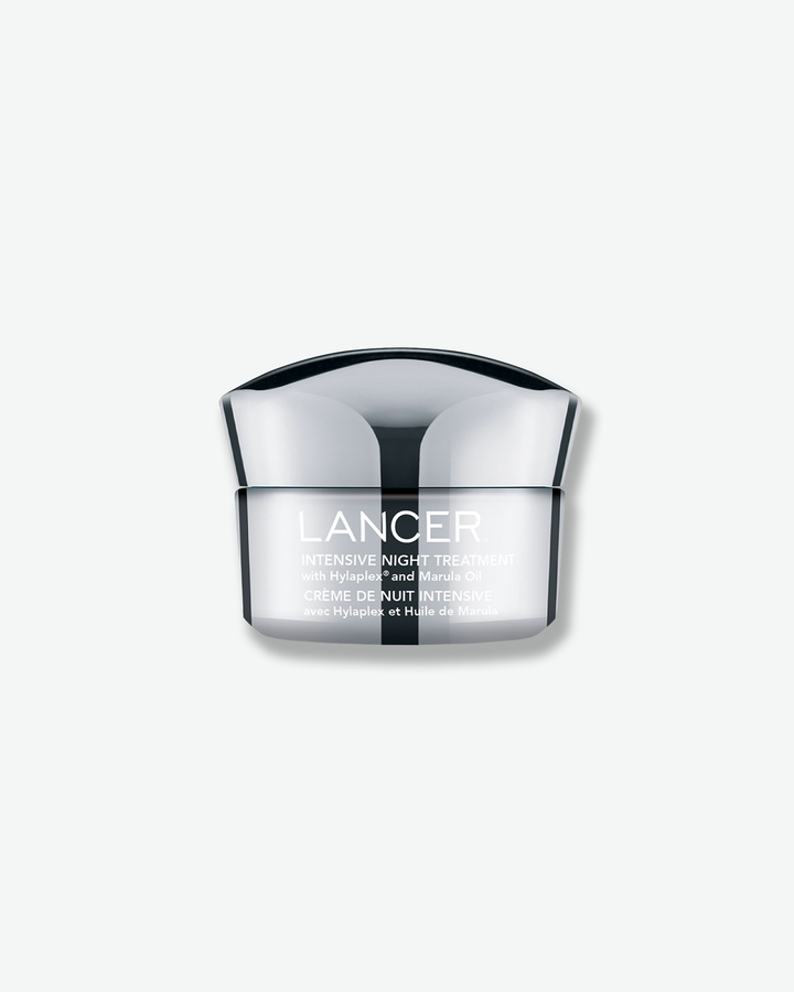 Front view of a Lancer Intensive Night Treatment jar against a plain gray background. The sleek cosmetic container features an opaque white base with silver-grey text detailing the formulation with Hylaplex and Marula Oil, crowned with a sculpted chrome metallic cap.