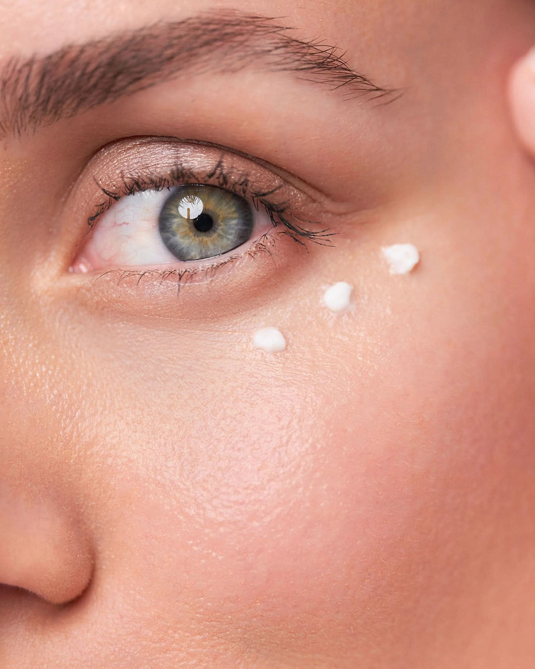 Close-up of a person's eye with light moisturizer application on the face.