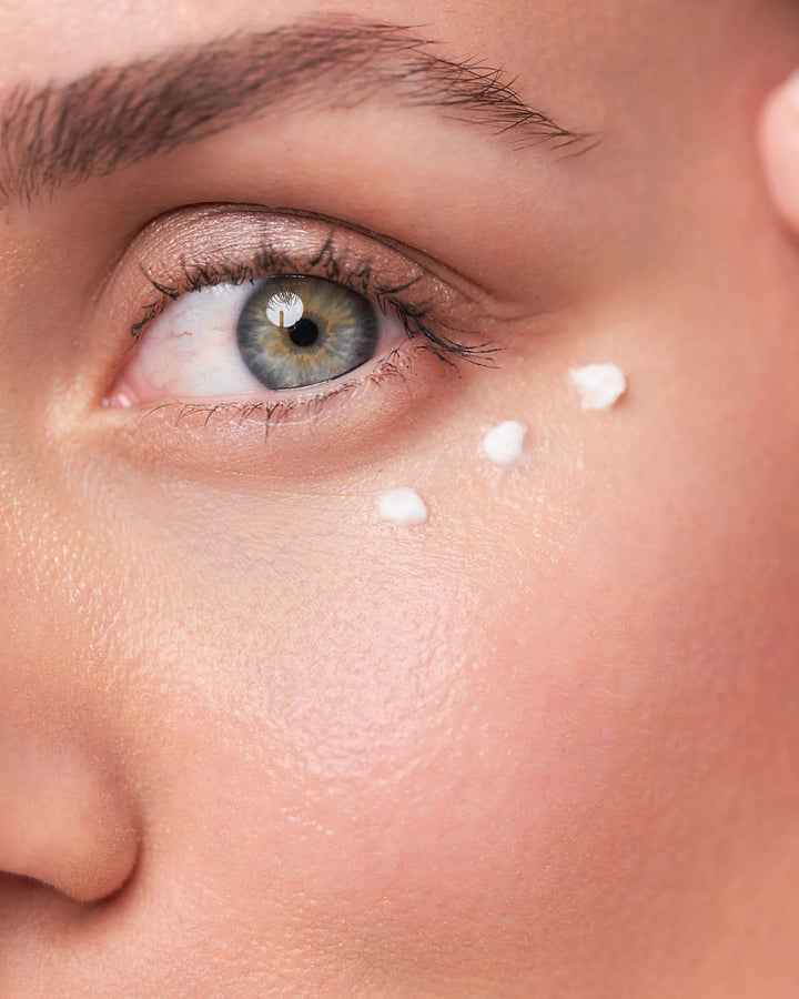 Close-up of a person's eye with light moisturizer application on the face.