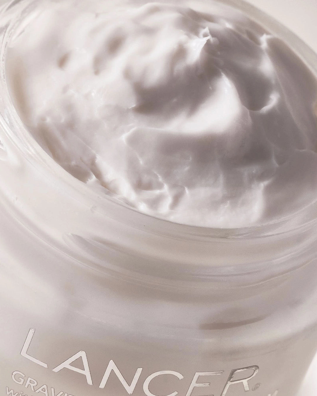 Close-up of a jar of Lancer skincare product with cream visible.
