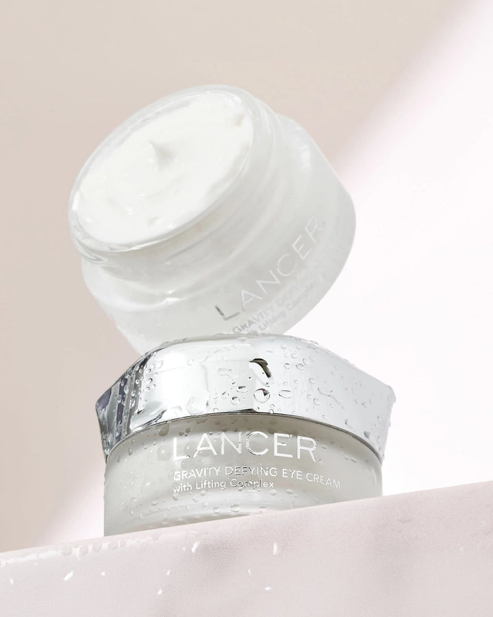 Two jars of Lancer eye cream on a light pink background