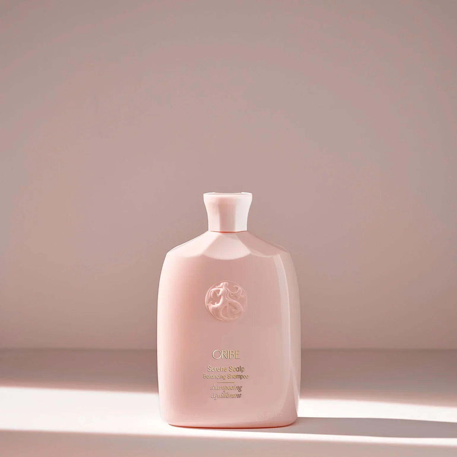 Pink bottle with a brand logo on a light pink background