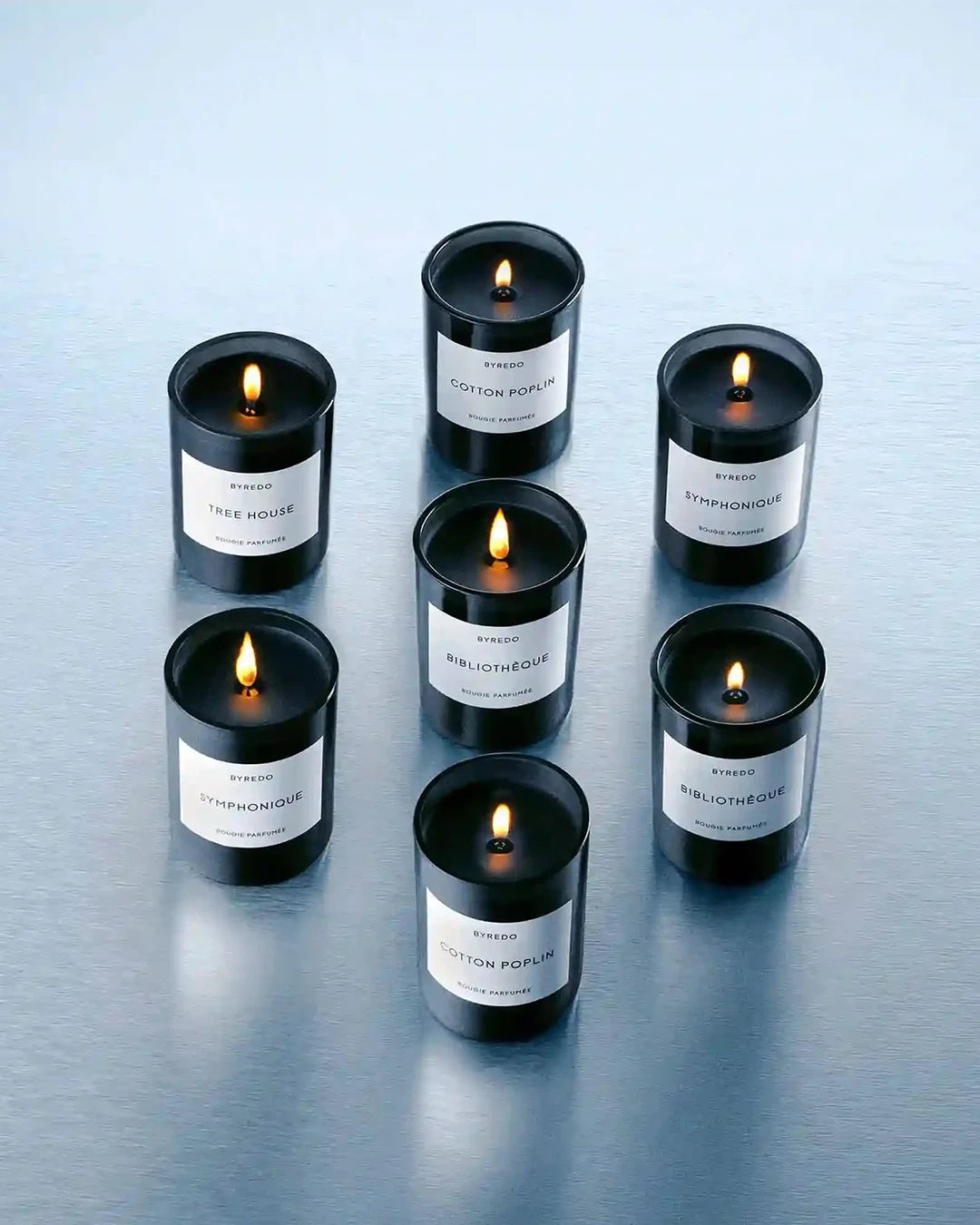 Set of black candles with white labels on a reflective surface
