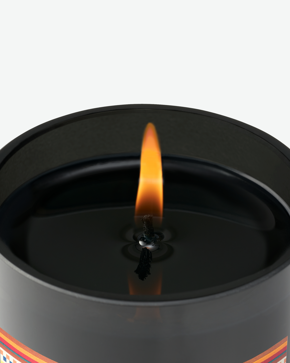 Close-up of a lit Byredo candle showing the flame, black wax, and black glass vessel.