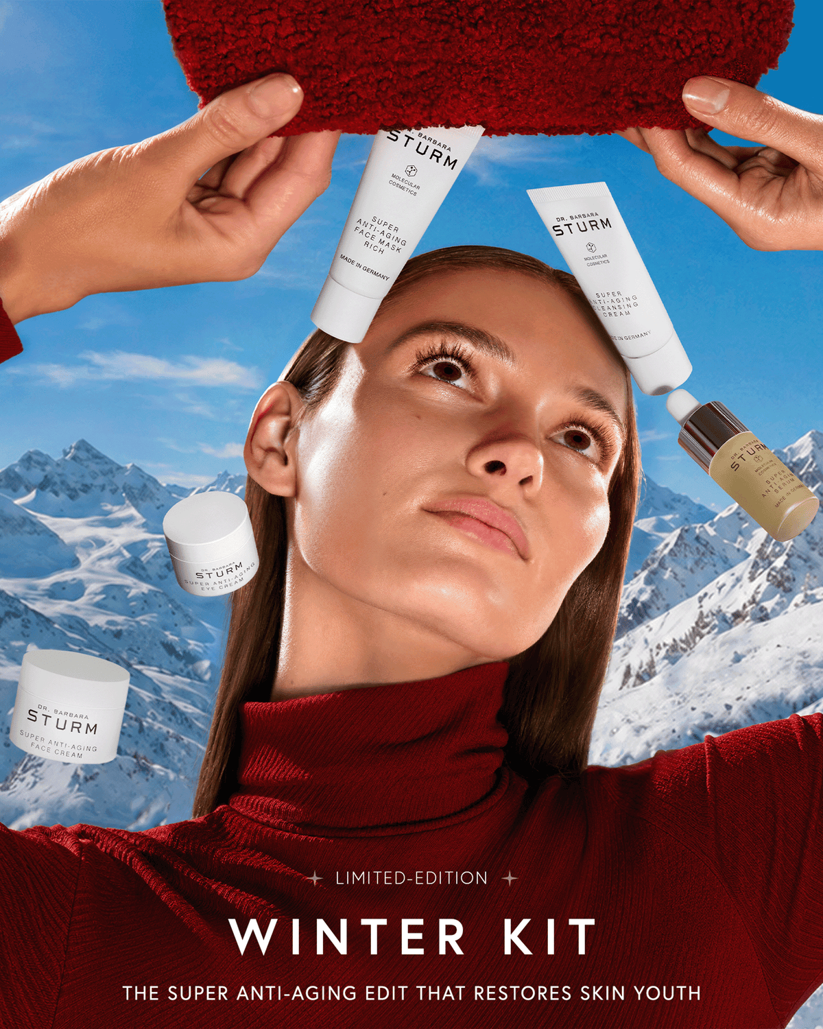Model in a red turtleneck surrounded by Dr. Barbara Sturm Super Anti-Aging skincare against a snowy mountain backdrop, highlighting the limited-edition Winter Kit.