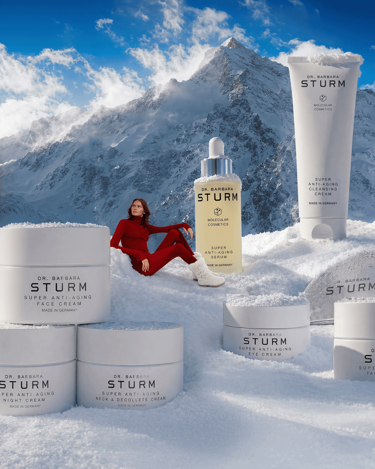 Dr. Barbara Sturm Super Anti-Aging skincare products displayed in snow with a dramatic alpine mountain backdrop.Dr. Barbara Sturm Super Anti-Aging skincare products displayed in snow with a dramatic alpine mountain backdrop.