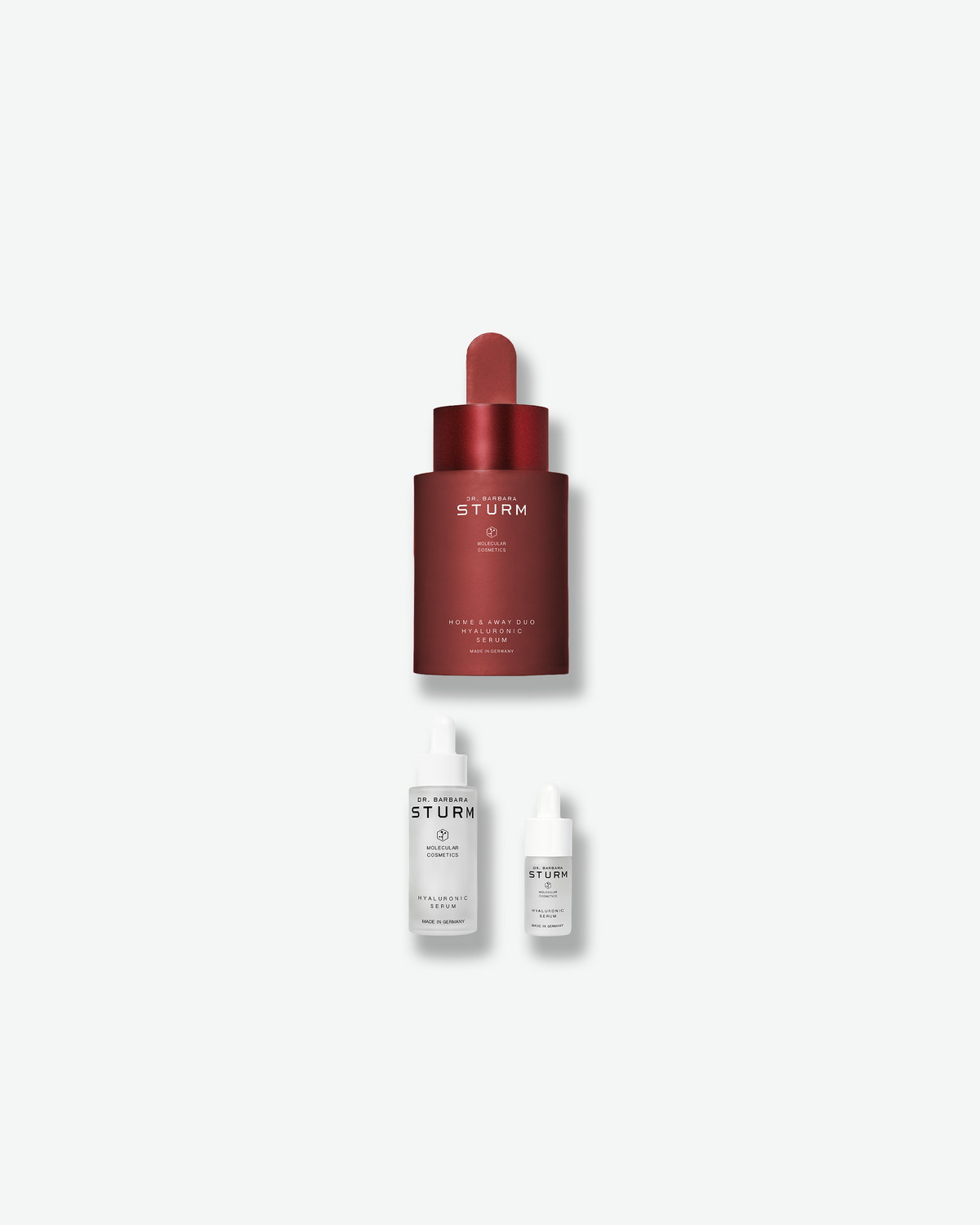 Dr. Barbara Sturm Home & Away Duo Hyaluronic Serum featuring the limited-edition red full-size bottle with two white Hyaluronic Serum bottles in full and travel sizes.