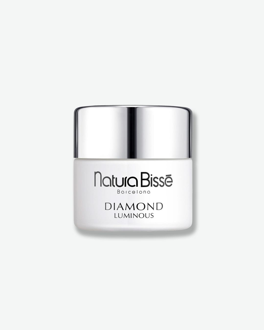 Front view of a Natura Bissé Diamond Luminous cream jar against a plain gray background. The container features a smooth, opaque matte white base showcasing the brand and product line in black text, capped with a polished silver metallic lid.