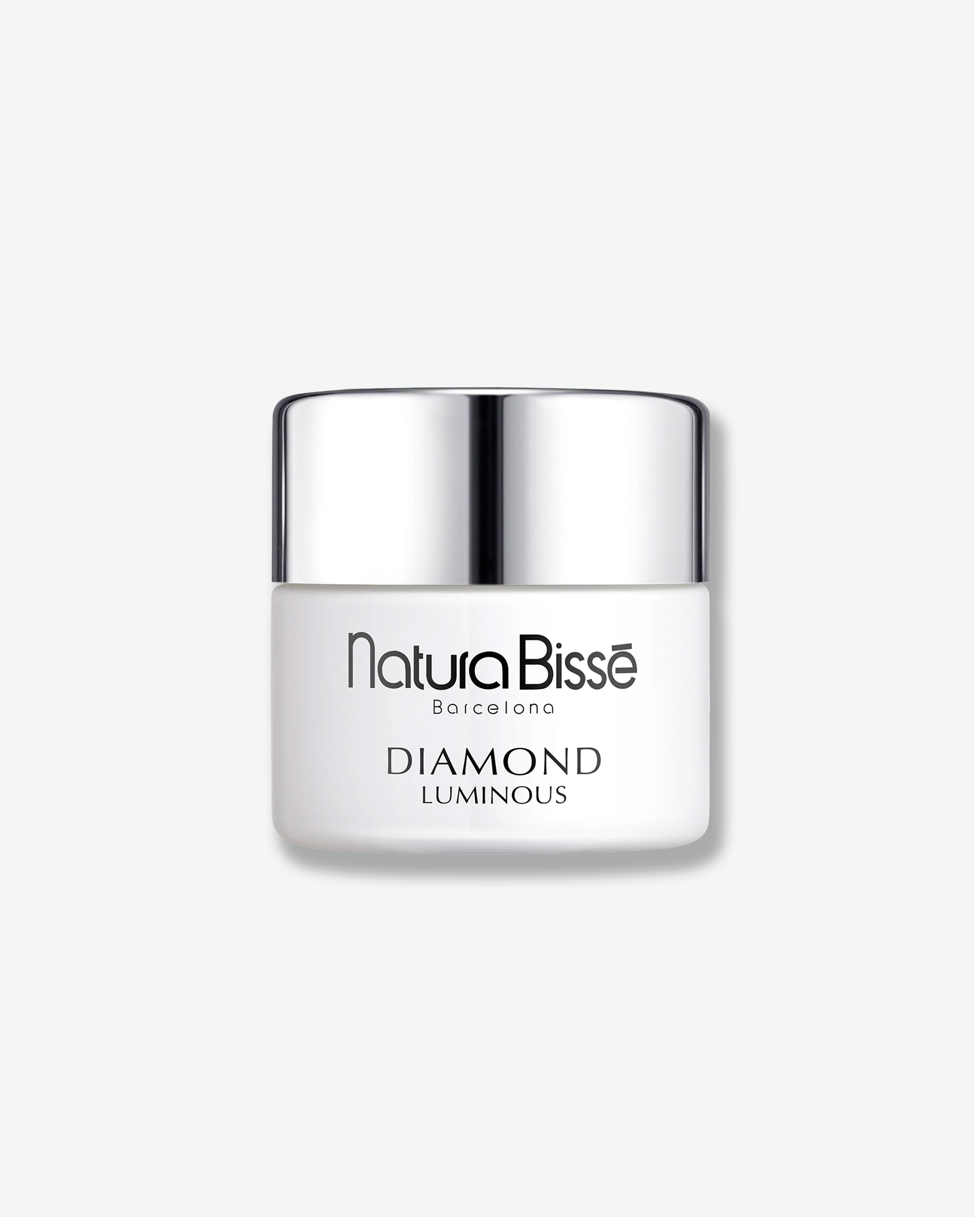 Front view of a Natura Bissé Diamond Luminous cream jar against a plain gray background. The container features a smooth, opaque matte white base showcasing the brand and product line in black text, capped with a polished silver metallic lid.