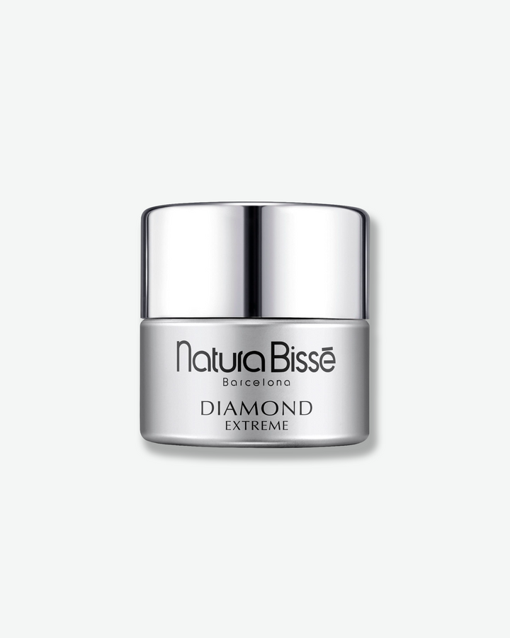 Front view of a standard-sized Natura Bissé Diamond Extreme jar against a plain gray background, featuring a clean, metallic silver-grey cylindrical body with black text and a polished silver lid.