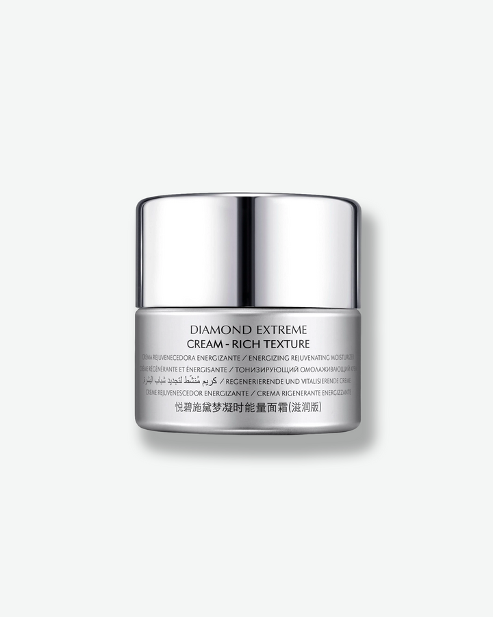 Front view of a Natura Bissé Diamond Extreme Cream - Rich Texture jar against a plain gray background. The silver-grey container is detailed with technical product descriptions in multiple languages on the lower half, topped with a reflective chrome cap.