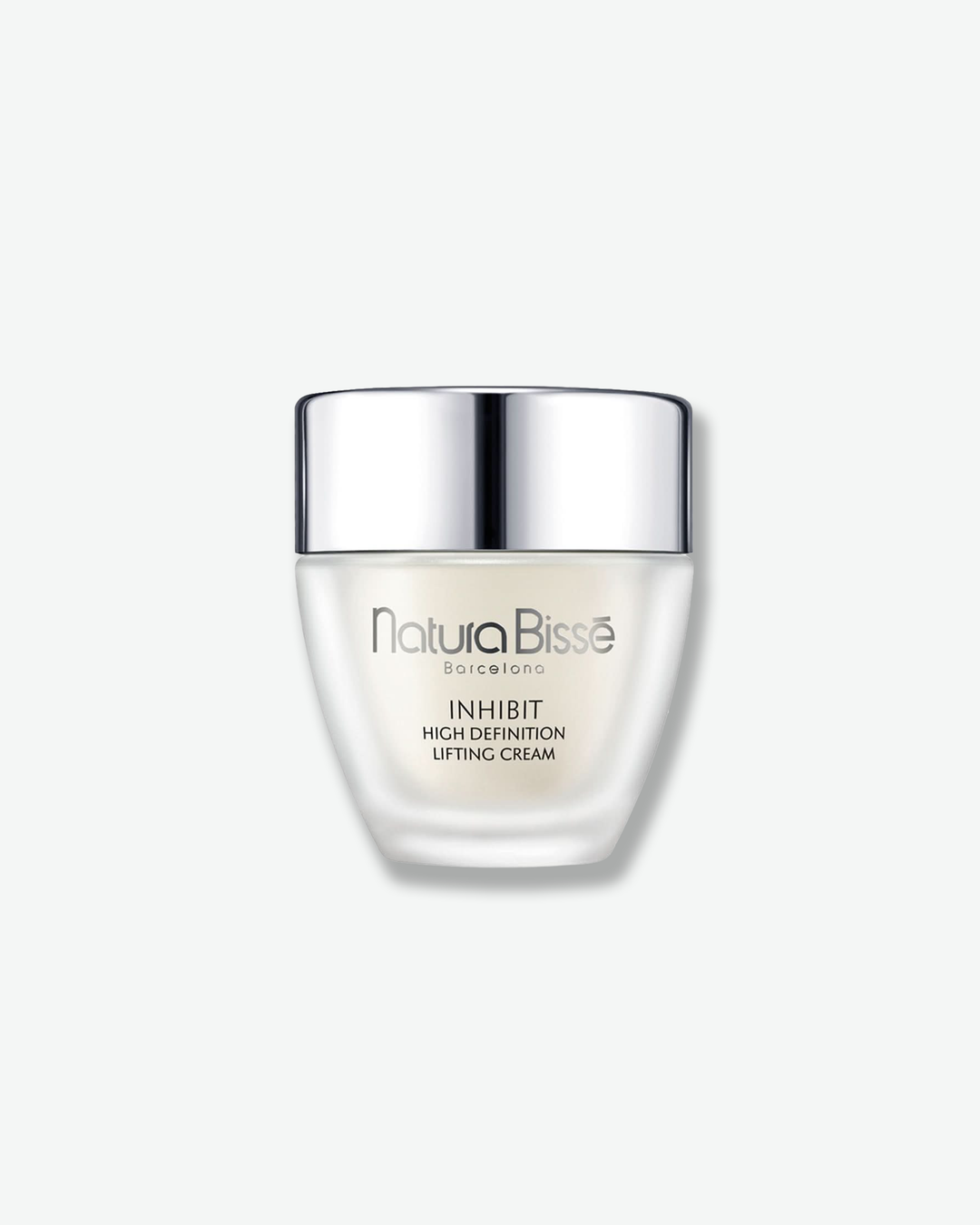 Front view of a Natura Bissé Inhibit High Definition Lifting Cream jar against a plain gray background. The unique container features a frosted white, tapered glass jar with a v-shaped silhouette, topped with a wide, polished silver metallic cap.