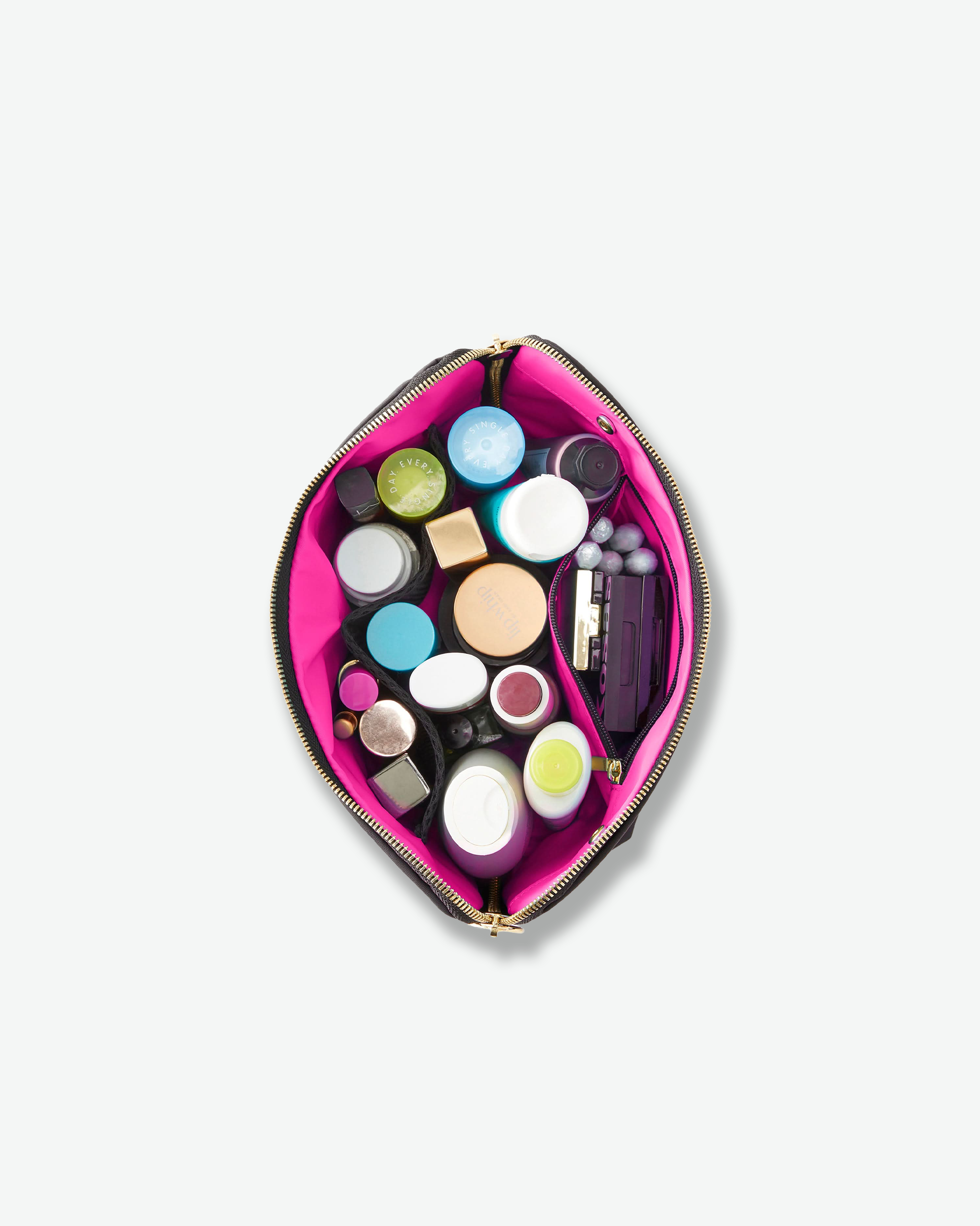 A bright pink makeup bag shown open from above, filled with assorted cosmetic jars and compacts on a light gray background.