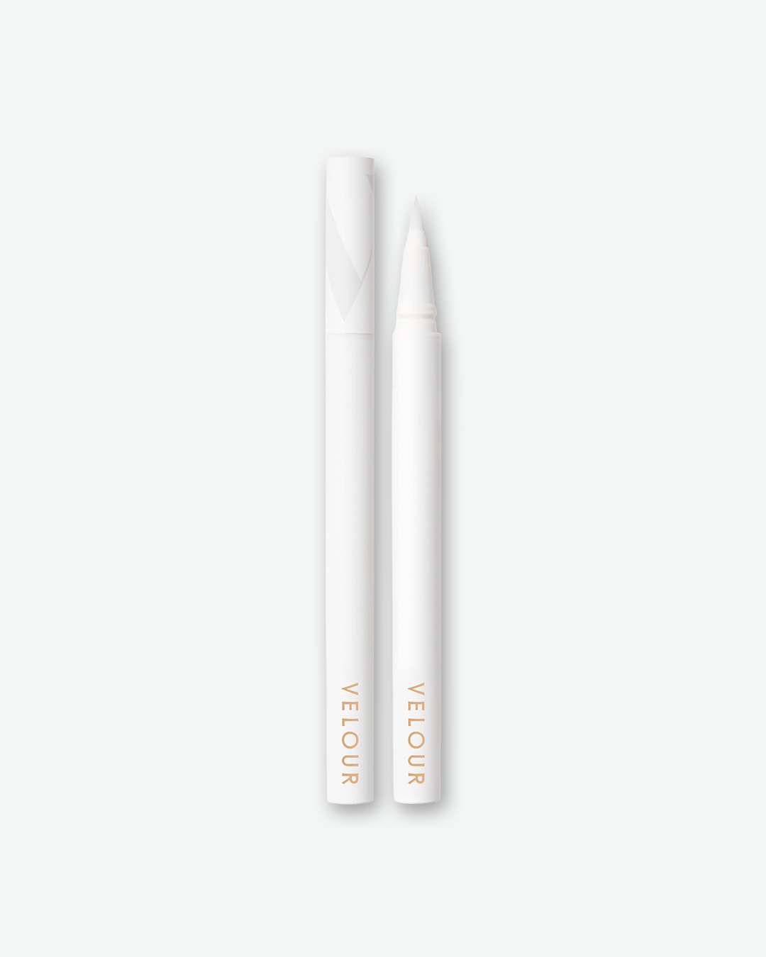 Product shot of a Velour liquid eyeliner pen shown next to its detached cap against a plain gray background. Both the slender pen and cap feature a matte white finish with minimalist gold branding text at the base. The pen is uncapped to display its fine, tapered precision felt tip.