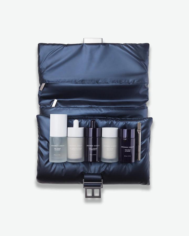 Set of skincare products in a navy blue travel case on a white background