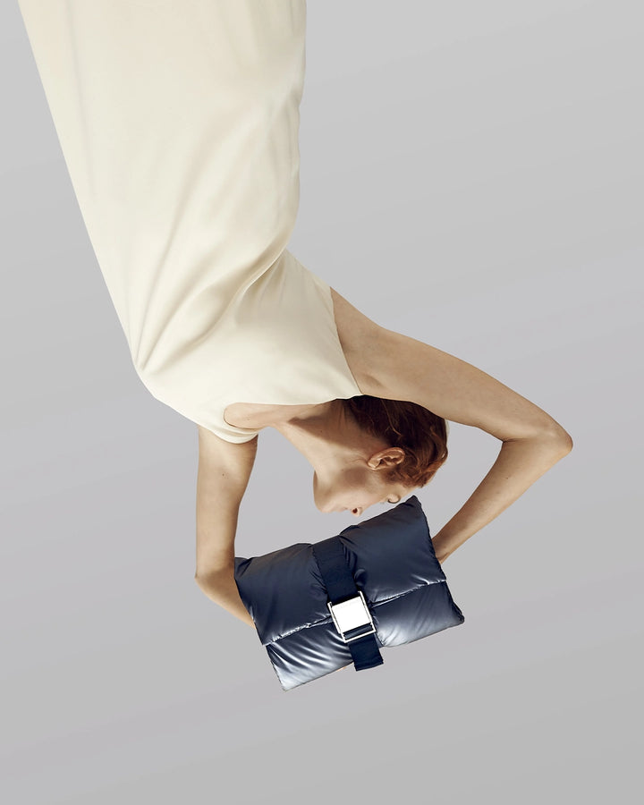 Person holding a black clutch bag against a plain background