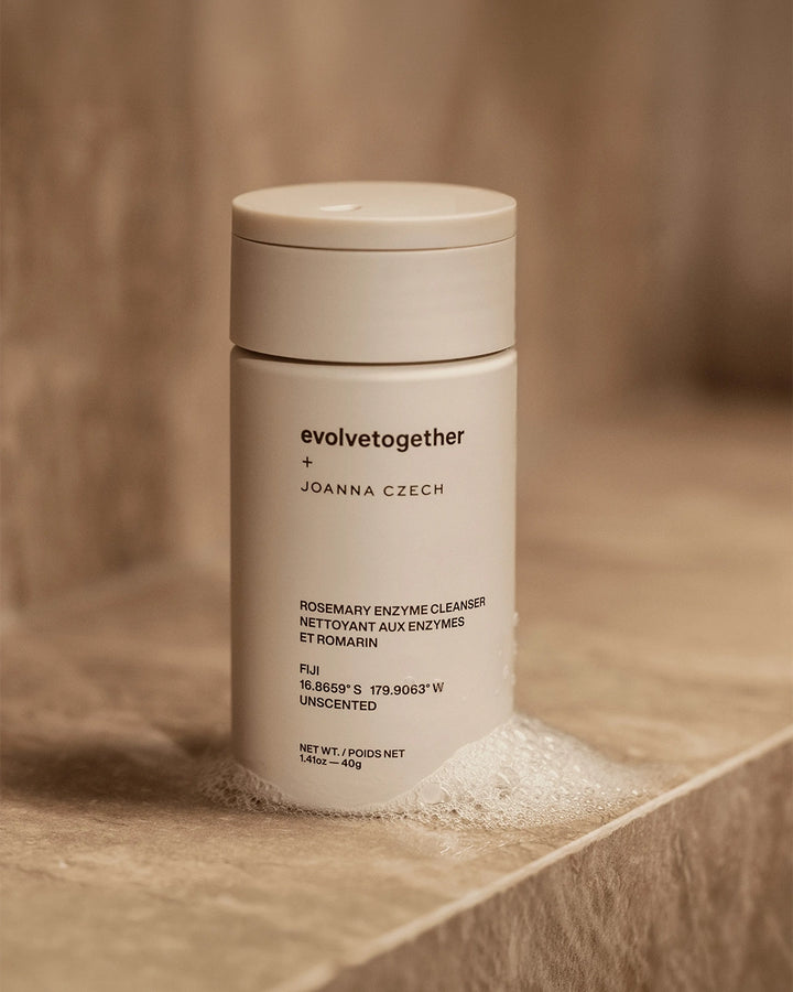 Beige skincare product container with 'evolvetogether' branding on a wooden surface.