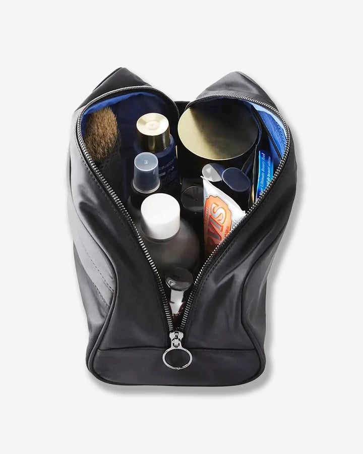Black toiletry bag with various items on a white background