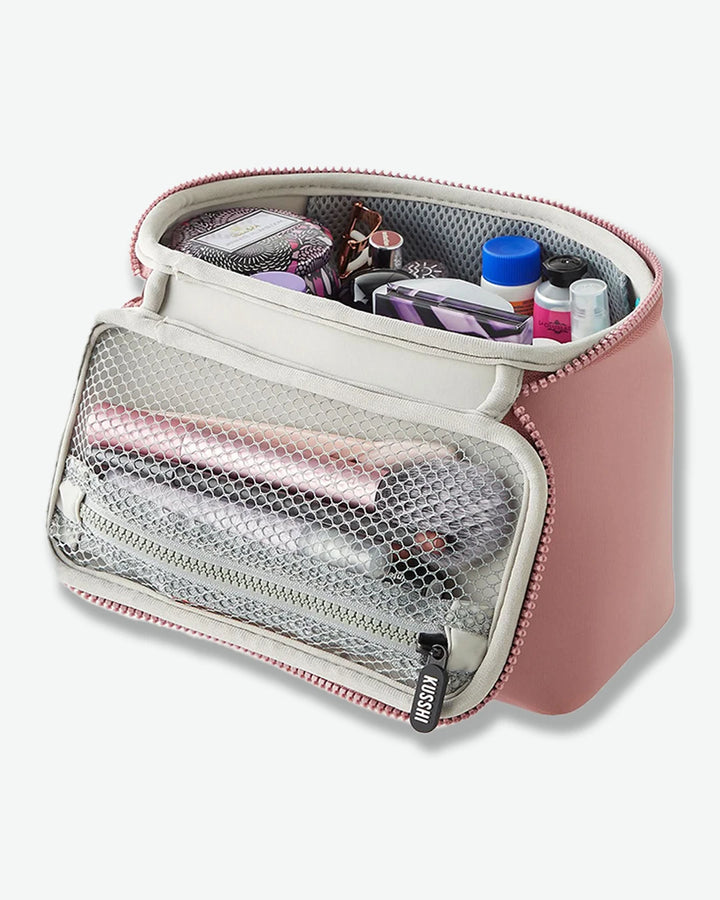 Pink toiletry bag with various items on a white background