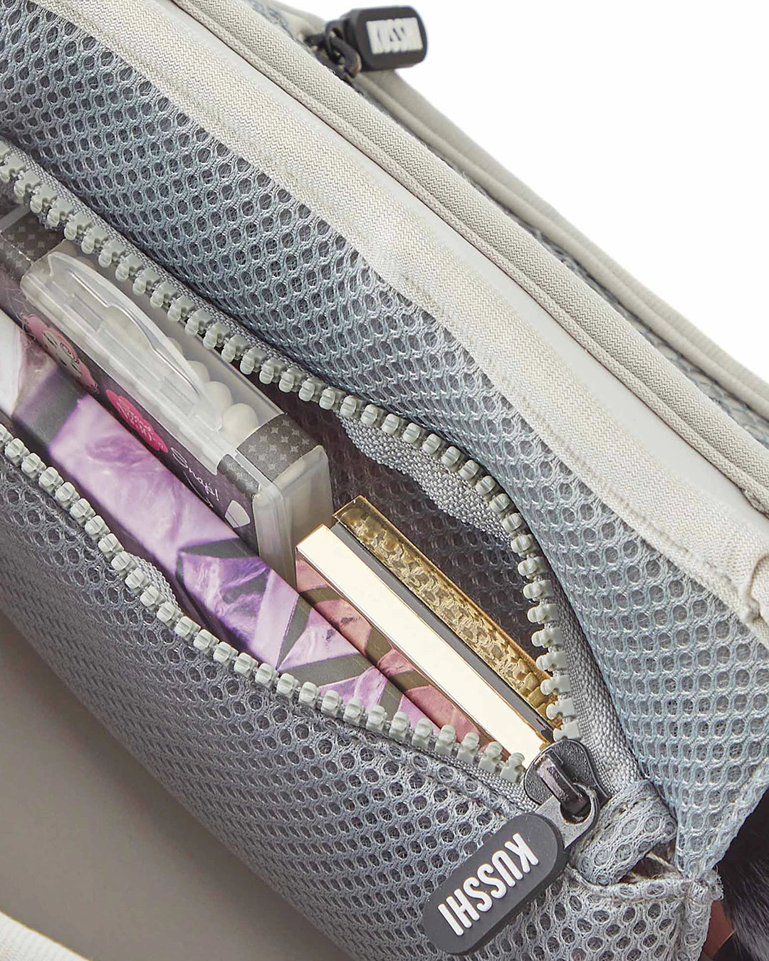 Gray travel pouch with floral item inside, featuring a visible brand label.