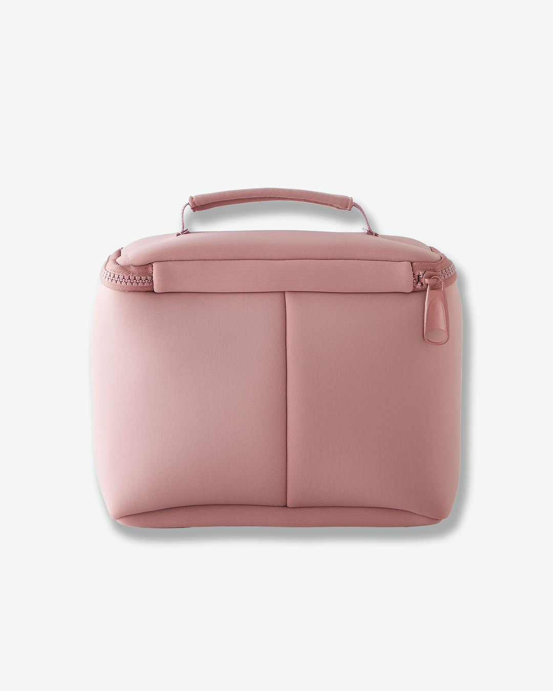 A studio back product shot of the same structured, dusty rose pink Kusshi makeup bag against a light gray background. This view highlights the back exterior, which features a vertical seam down the middle dividing it into two slip pockets. The thick top handle is visible, and the matching pink zipper pull sits on the upper right side.