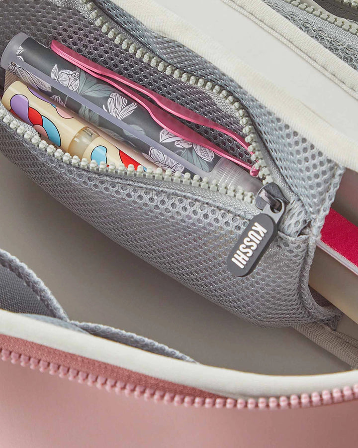 Gray mesh pouch with a pink zipper containing stationery items, branded 'Kusshi'.