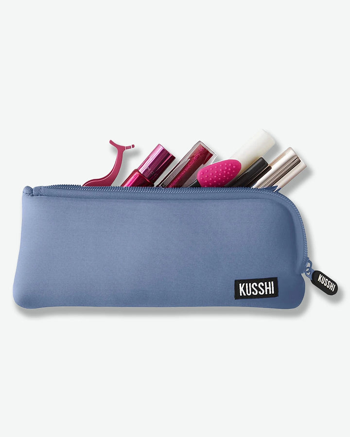 Blue makeup pouch with cosmetic items on a white background
