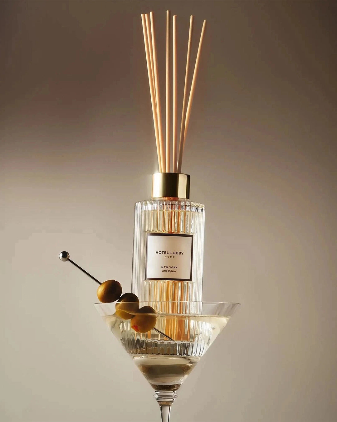 Diffuser with wooden sticks in a glass container on a neutral background