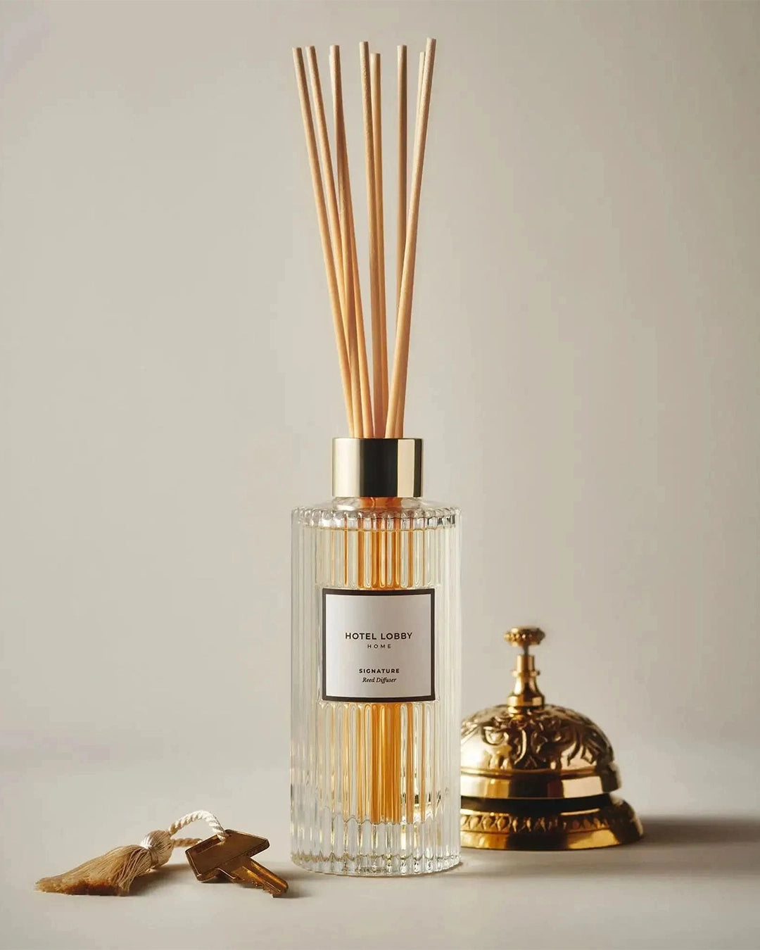 Diffuser with wooden sticks, key, and bell on a neutral background