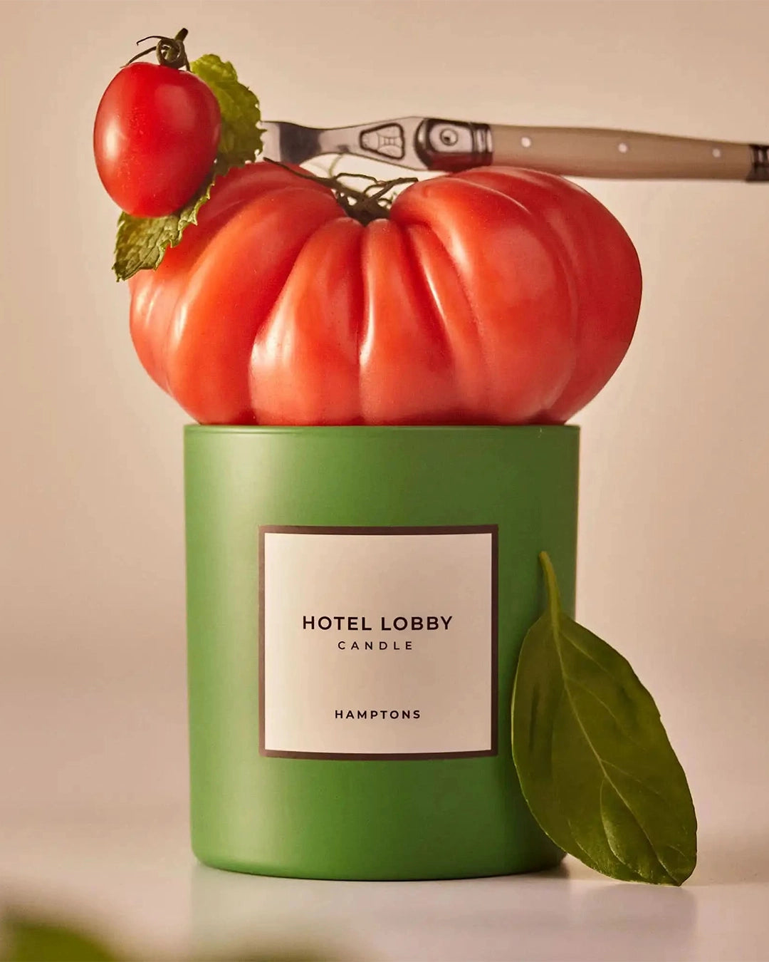 Green candle labeled 'Hotel Lobby Candle' with tomatoes and a knife on top