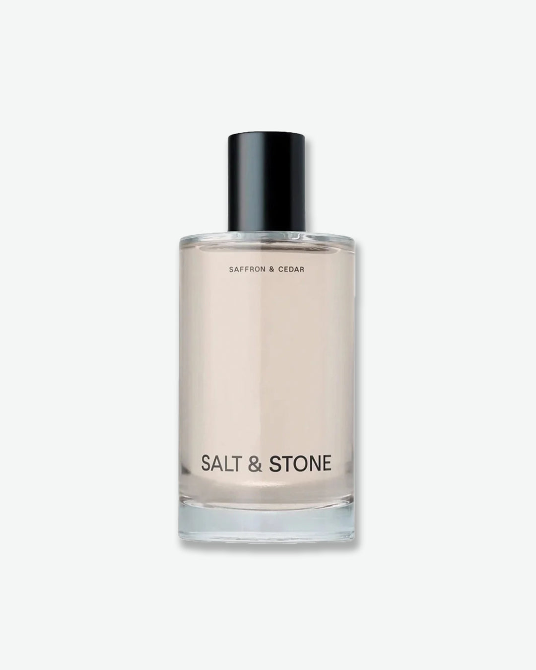 Salt & Stone Saffron & Cedar product in a minimalist clear glass bottle with a black cylindrical cap and crisp black text, isolated against a light grey background.