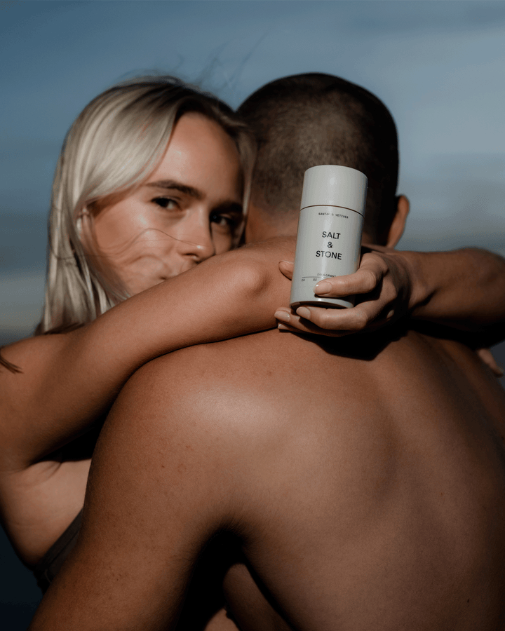 Woman holding a Salt & Stone deodorant stick while hugging a man.