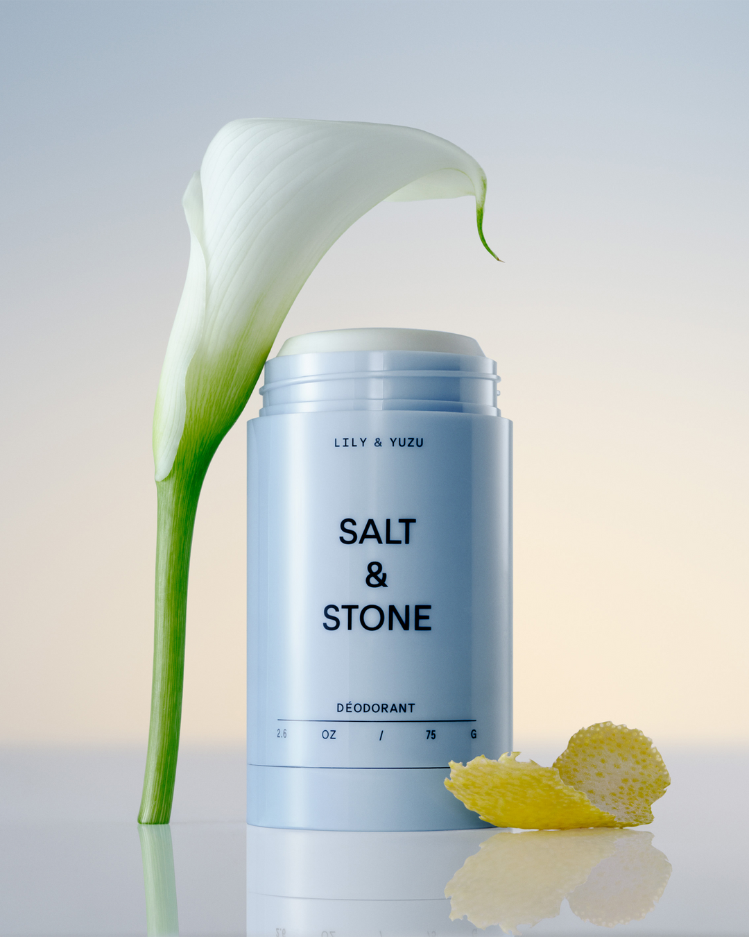 Salt & Stone Lily & Yuzu deodorant stick with a white flower and citrus peel.