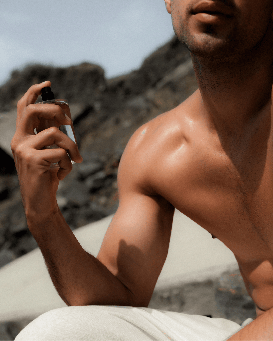 Man holding a Salt & Stone perfume bottle outdoors.