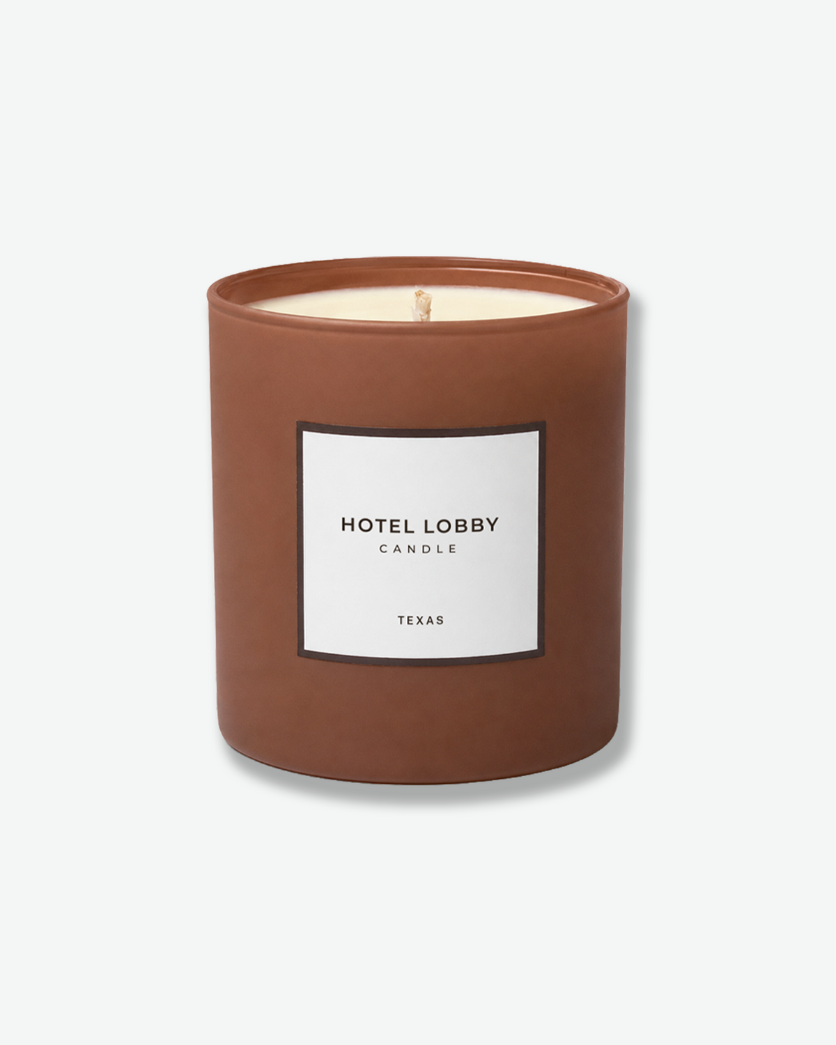 Hotel Lobby Candle Texas candle in a warm brown vessel with a white label.